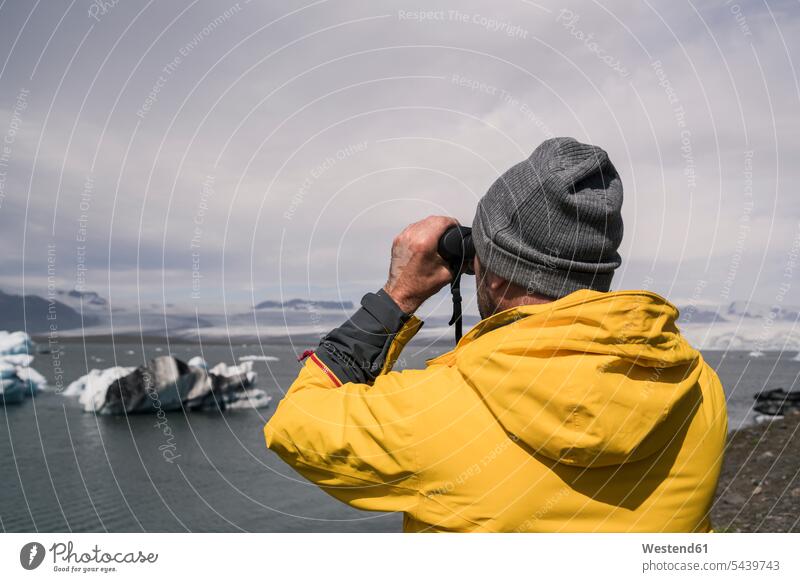 Mature man watching Vatnajokull glacier with binoculars, Iceland human human being human beings humans person persons caucasian appearance caucasian ethnicity