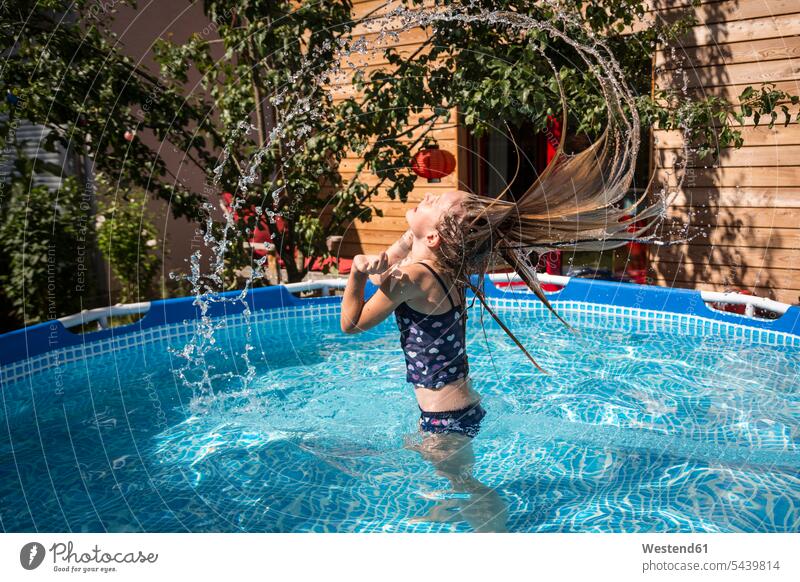Girl in the garden pool splashing with water girl females girls swimming pool pools swimming pools child children kid kids people persons human being humans