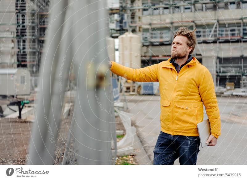 Man holding laptop, construction site in the background Job Occupation Work Responsibility responsible engineer engineers expertise competence competent working