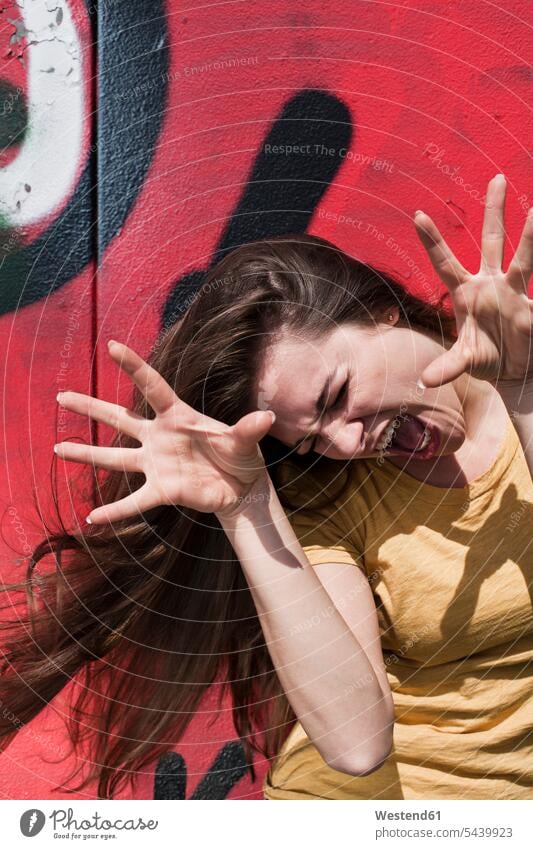 Portrait of young woman making a face in front of a graffiti caucasian caucasian ethnicity caucasian appearance European sunlight standing shadow shadows finger