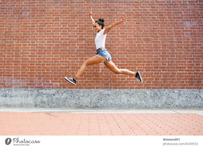 Happy young woman in sportswear jumping midair - a Royalty Free