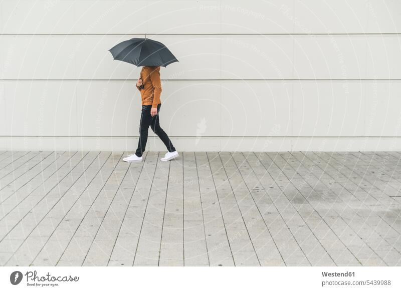 Young man with umbrella walking in the street human human being human beings humans person persons caucasian appearance caucasian ethnicity european adult