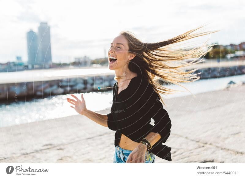 Exuberant young woman at the seafront exuberance hilarity Frolic exuberant laughing Laughter females women happiness happy positive Emotion Feeling Feelings