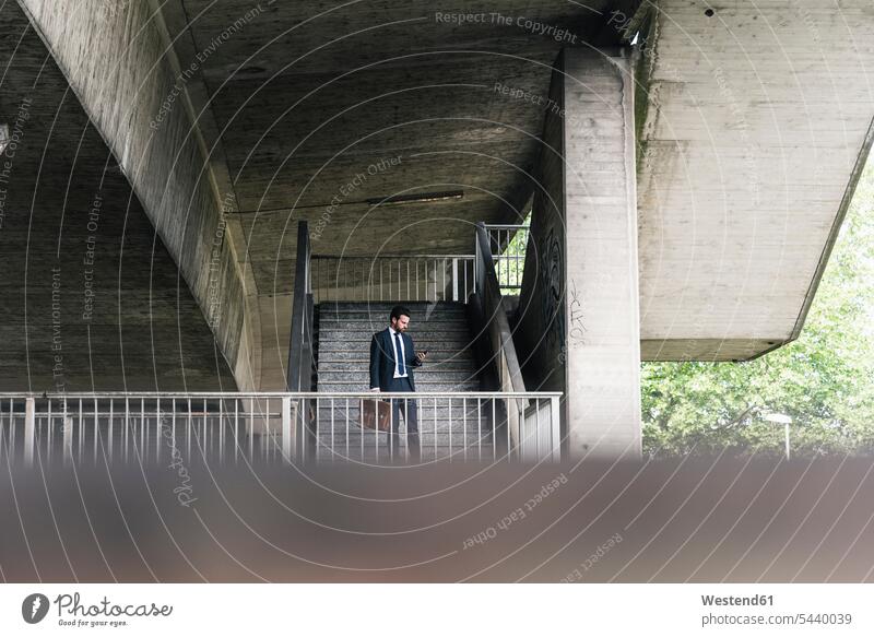 Businessman at underpass checking cell phone mobile phone mobiles mobile phones Cellphone cell phones Business man Businessmen Business men telephones