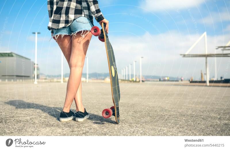 Back view of young woman with longboard in front of beach promenade, partial view females women female skateboarder female skater female skateboarders Longboard