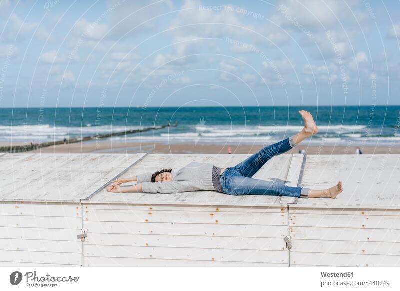 Woman lying on wooden box on the beach laying down lie lying down beaches woman females women relaxed relaxation Adults grown-ups grownups adult people persons