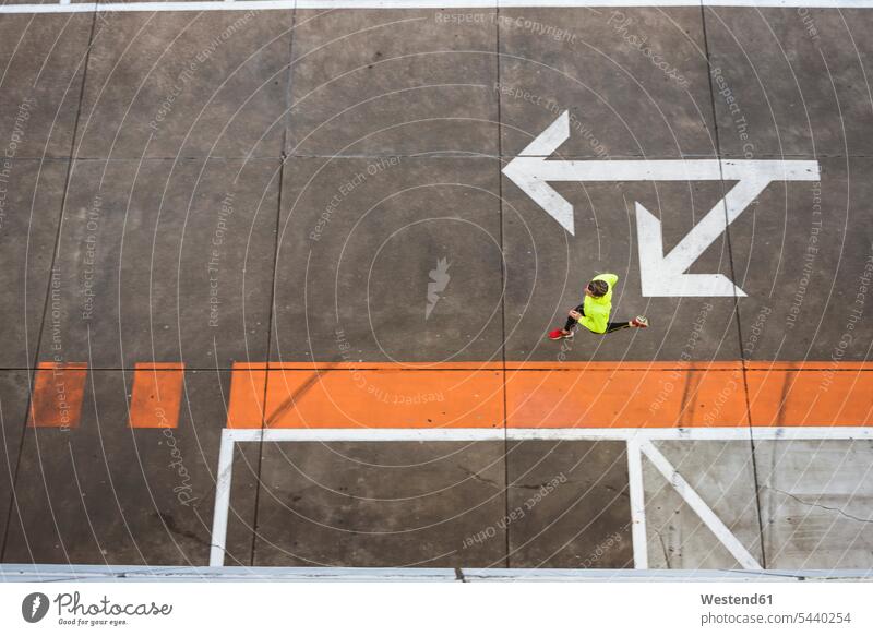 Young man running on parking level men males exercising exercise training practising Jogging Adults grown-ups grownups adult people persons human being humans