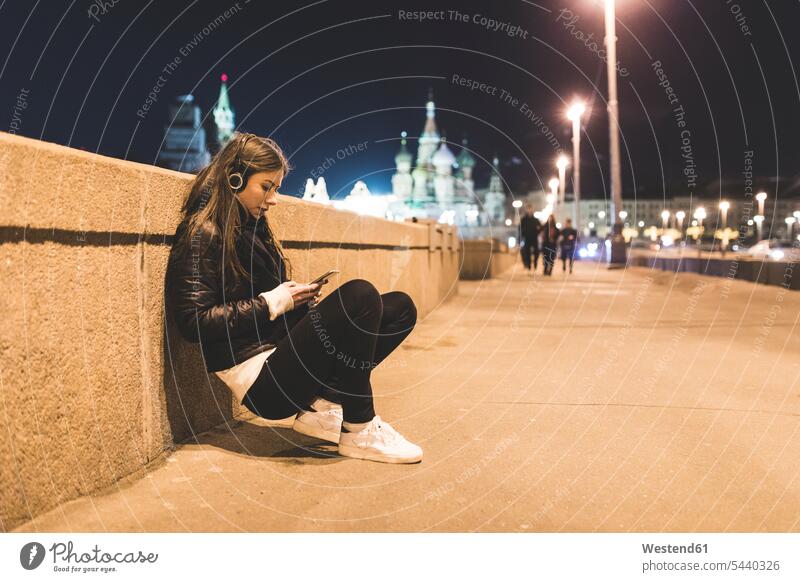 Russia, Moscow, beautiful woman listening music in the city at night females women town cities towns hearing by night nite night photography Adults grown-ups