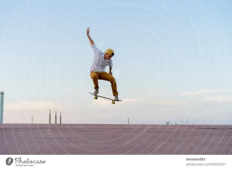 Young man doing a skateboard trick on a lane at dusk Trick atmosphere atmospheric evening evening twilight skateboarder skater skateboarders skaters Lane