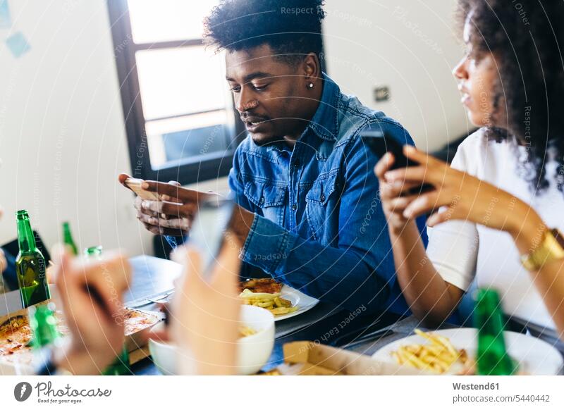 Friends using cell phones at dining table mobile phone mobiles mobile phones Cellphone friends eating Table Tables telephones communication telecommunication