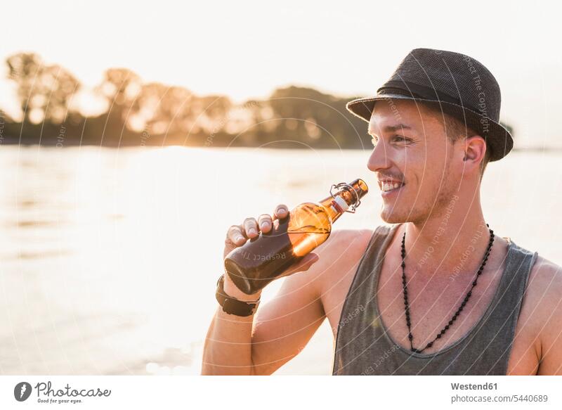 Portrait of young man wearing a hat at the riverbank relaxed relaxation smiling smile men males Beer Beers Ale relaxing Adults grown-ups grownups adult people