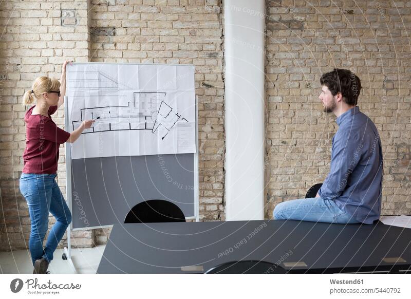 Businesswoman explaining new project to young colleague projects discussing discussion pointing point at pointing at show showing coworker colleagues coworkers