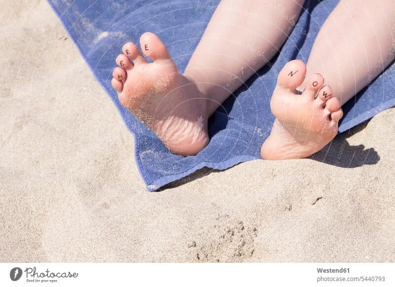 Feet of woman with writing 'Here Now' at the toes beach beaches foot human foot human feet people persons human being humans human beings holidays towel towels