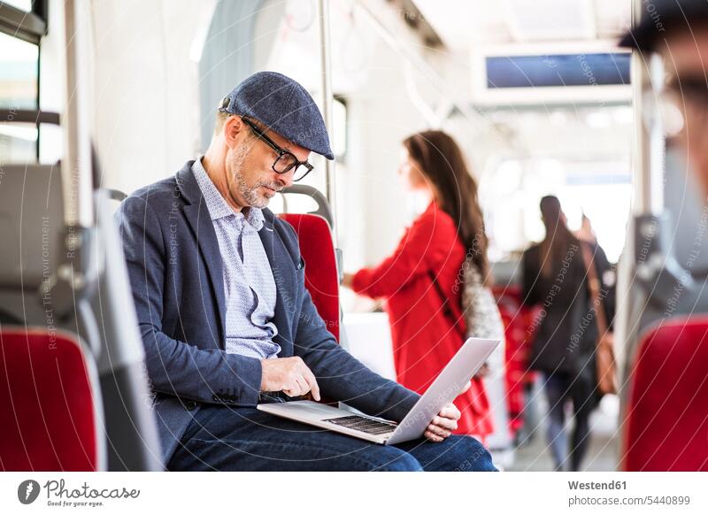 Businessman using laptop in bus busses commuter commuters Laptop Computers laptops notebook men males motor vehicle road vehicle road vehicles motor vehicles