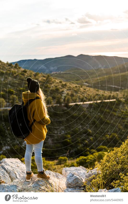 Young woman standing on rock in nature looking at view females women Adults grown-ups grownups adult people persons human being humans human beings backpack