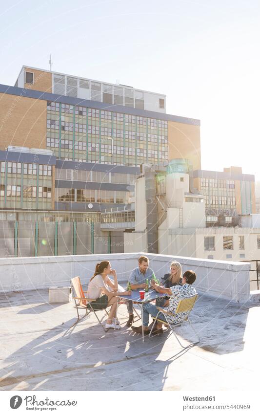 Friends having a rooftop party on a beautiful summer evening carefree friends enjoying indulgence enjoyment savoring indulging roof terrace deck summer time