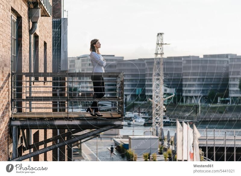 Businesswoman standing on a balcony, with eyes closed businesswoman businesswomen business woman business women thinking balconies smart smart casual