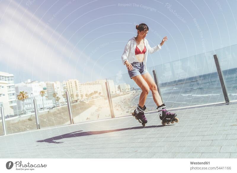 Young woman inline skating on boardwalk at the coast inline skates inliners riding females women Rollerblades rollerskating roller skating rollerblading sport