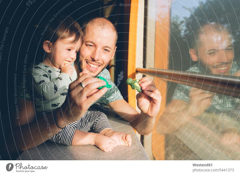 Father playing with his baby girl while traveling by train infants nurselings babies father pa fathers daddy dads papa window windows travelling people persons