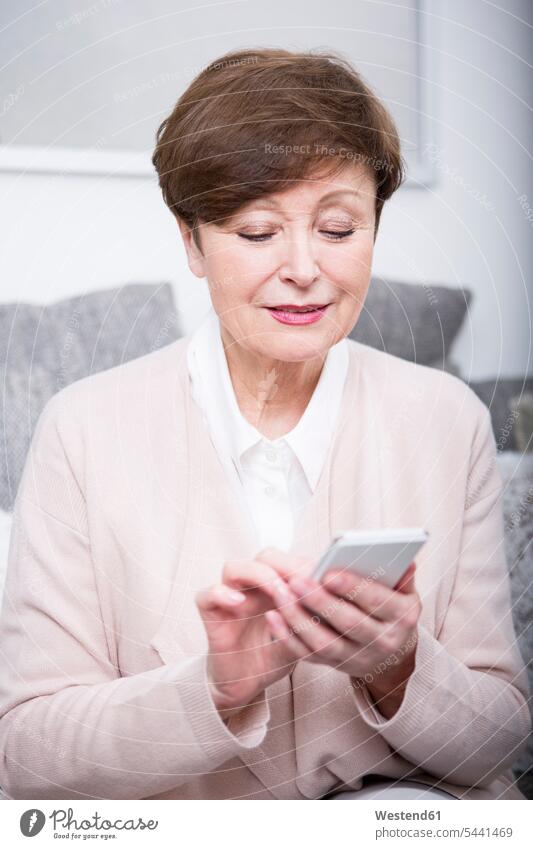Portrait of a senior woman using smart phone sitting Seated senior women elder women elder woman old females senior adults Adults grown-ups grownups people