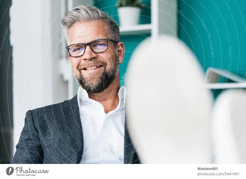 Businessman sitting in office with feet on desk Office Offices Business man Businessmen Business men business people businesspeople business world business life