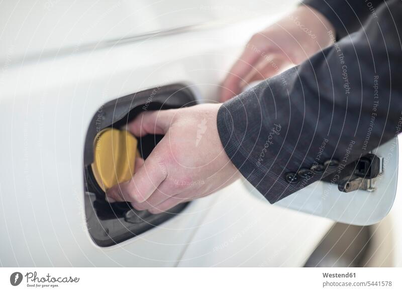 Man closing petrol cap of car at fuel station automobile Auto cars motorcars Automobiles fuelling fueling refuelling refueling petrol station petrol stations