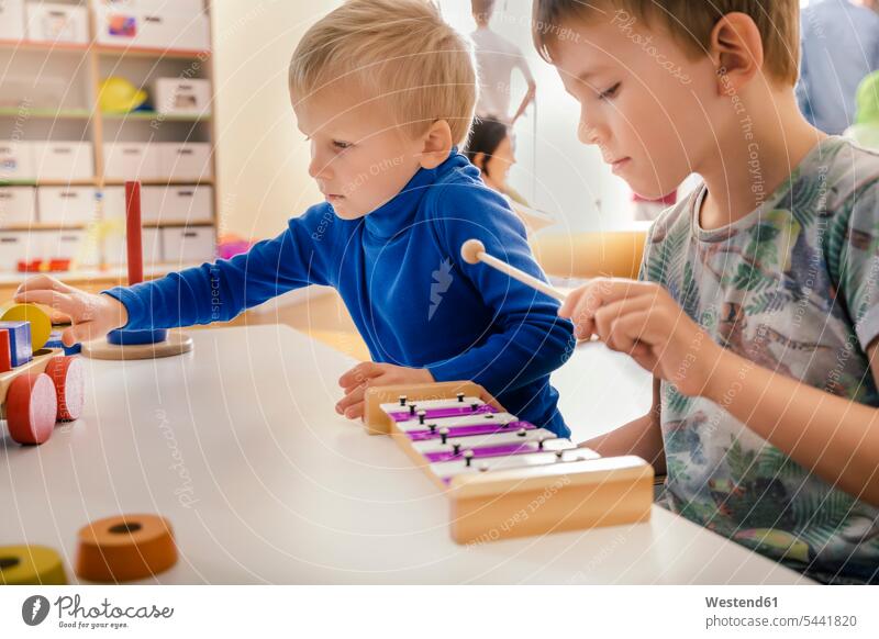 Two boys playing with musical instruments and toys in kindergarten child children kid kids males nursery school people persons human being humans human beings