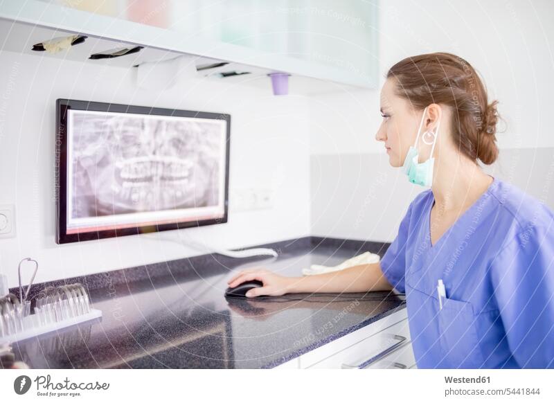 Female dentist examining x-ray of teeth on screen x-ray image x-rays radiography radiographies tooth woman females women female dentist female dentists