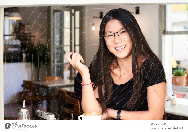 Asian young woman smiling at camera in a coffee shop smile portrait portraits female Asian female Asians females women sitting Seated Cafe Shop cafe