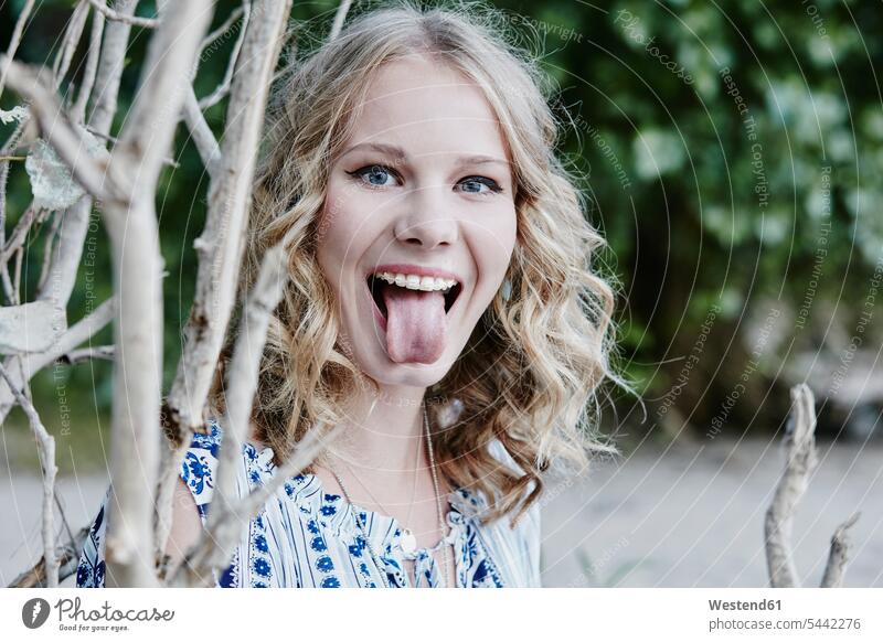 Portrait of teenage girl sticking out tongue in nature cheeky impertinent Cheekiness impertinence Teenage Girls female teenagers portrait portraits Teenager
