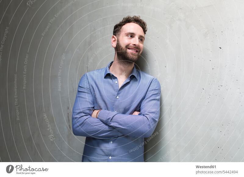 Smiling man leaning against concrete wall smiling smile concrete walls men males Adults grown-ups grownups adult people persons human being humans human beings