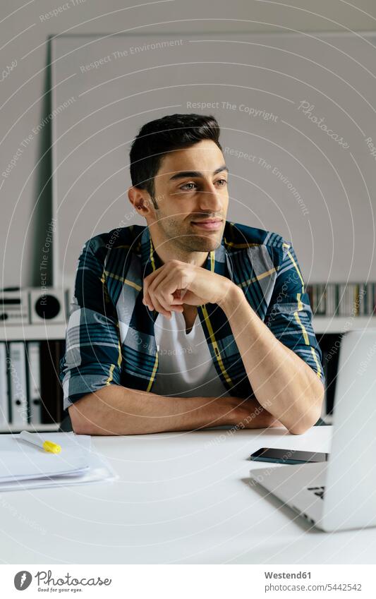 Young man using laptop at desk in office Laptop Computers laptops notebook Businessman Business man Businessmen Business men desks use offices office room