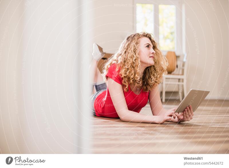 Young woman in new home lying on floor with tablet females women laying down lie lying down flat flats apartment apartments digitizer Tablet Computer Tablet PC