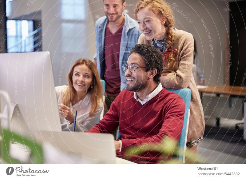 Colleagues looking over shoulder of young man working in modern office team Female Colleague watching offices office room office rooms smiling smile At Work PC