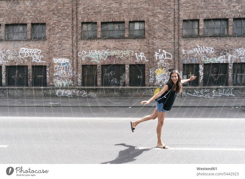 Carefree woman on the street females women standing road streets roads Adults grown-ups grownups adult people persons human being humans human beings balance