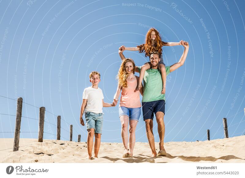 Netherlands, Zandvoort, happy family walking on the beach - a