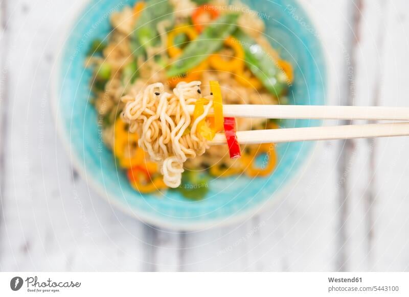 Chopsticks with mie noodles, chili pod and bell pepper, close-up garnished prepared snow pea snow peas ready to eat ready-to-eat boiled cooked hearty