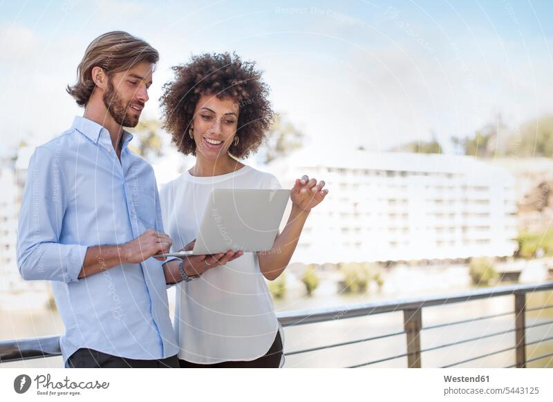 Businessman and woman having a meeting outdoors, using laptop Passion passionate colleagues casual discussing discussion Laptop Computers laptops notebook