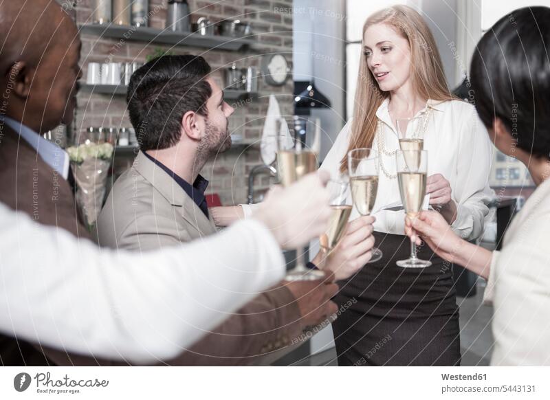 Friends holding champagne glasses socializing in kitchen home at home friends celebrating celebrate partying Sparkling Wine friendship Alcohol