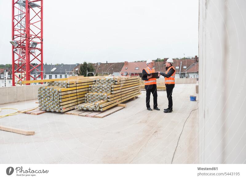 Two men wearing safety vests talking on construction site working At Work man males speaking Building Site sites Building Sites construction sites architect