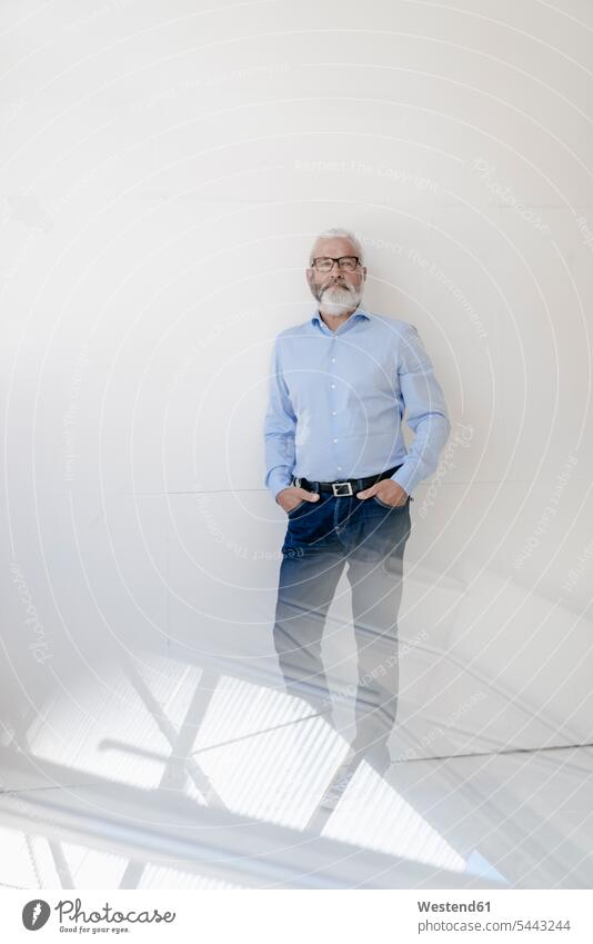 Mature man with beard and glasses standing at a wall Businessman Business man Businessmen Business men males business people businesspeople business world