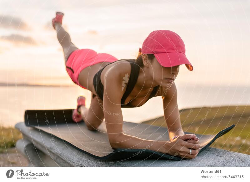 Young woman doing strength training on a bench at the sea Strength strong Force Strengthy Power warming up warm up benches exercising exercise practising fit