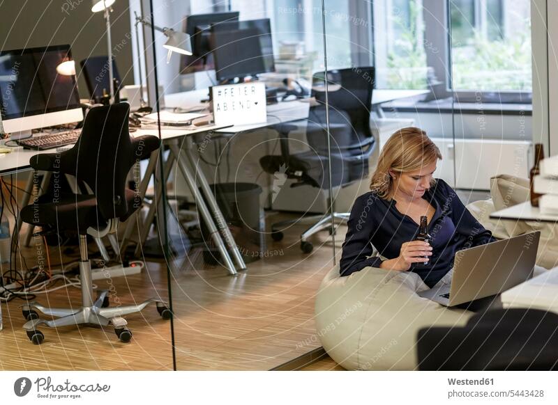 Businesswoman with beer bottle and laptop in office Laptop Computers laptops notebook businesswoman businesswomen business woman business women drinking offices