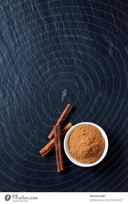 Bowl of cinnamon powder and cinnamon sticks on slate food and drink Nutrition Alimentation Food and Drinks close-up close up closeups close ups close-ups Bowls