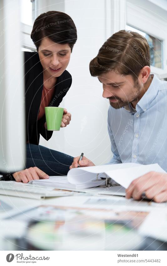 Colleagues working together at desk in office offices office room office rooms colleagues At Work talking speaking workplace work place place of work desks