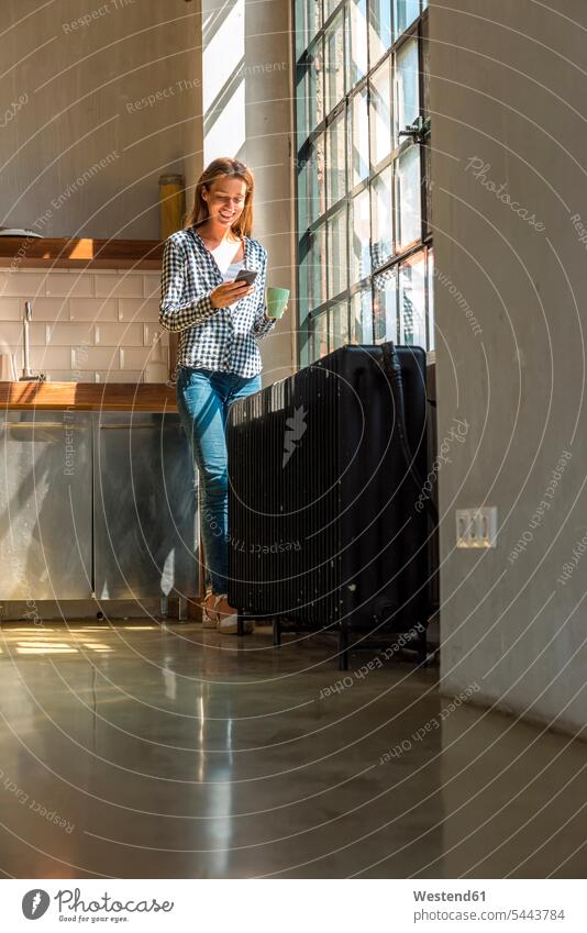 Young woman entrepreneur standing in company kitchen, drinking coffee, using smartphone young Coffee Taking a Break resting break business people businesspeople