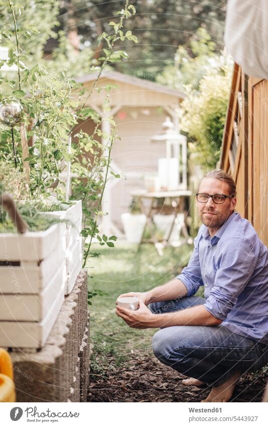 Man with cup of coffee relaxing in garden man men males Coffee Cup Coffee Cups gardens domestic garden relaxed relaxation Adults grown-ups grownups adult people