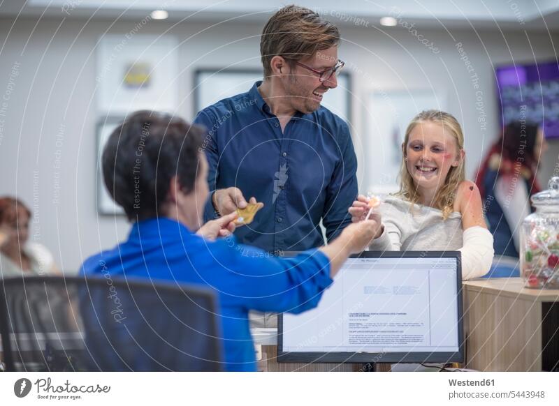 Sick girl getting lollipop from receptionist in hosptal hospital Medical Clinic daughter daughters doctor physicians doctors patient father fathers daddy dads