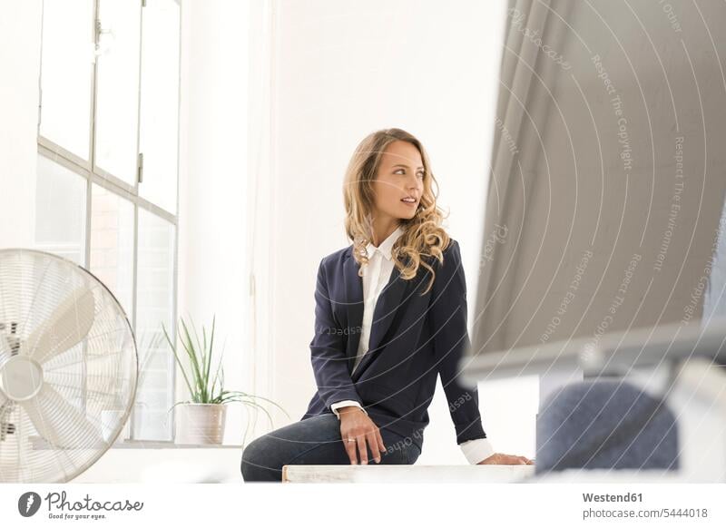 Businesswoman sitting on desk in her office offices office room office rooms Seated businesswoman businesswomen business woman business women entrepreneur