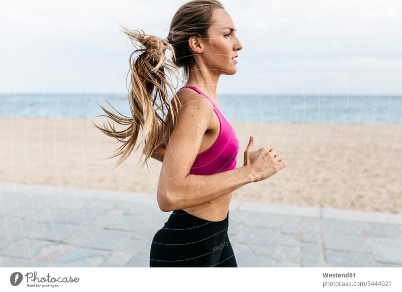 Young woman running at the beach exercising exercise training practising beaches females women Adults grown-ups grownups adult people persons human being humans